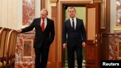 El presidente ruso, Vladimir Putin (izquierda) y el primer ministro Dmitry Medvedev, hablan antes de una reunión con miembros del gobierno en Moscú, el 15 de enero de 2020.