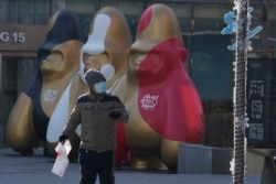 A man wearing a mask walks near decorations at a shopping mall in Beijing, Dec. 14, 2021. Chinese state media said Monday, Dec. 13, 2021, that the first case of the omicron variant of COVID-19 has been detected in the country's mainland in Tianjin city ju