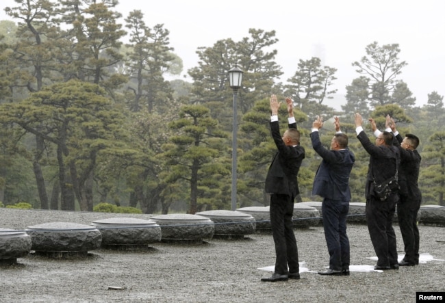 People raise hands as they shout 'banzai', or cheers, facing the Imperial Palace on the day of the Emperor Akihito's abdication in Tokyo, April 30, 2019.