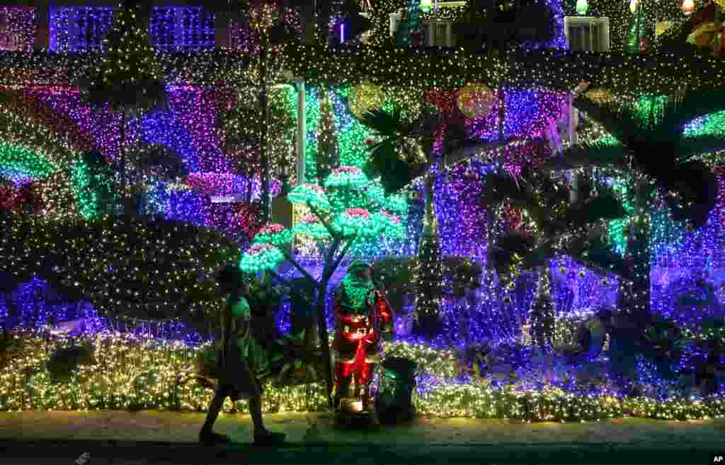A boy walks in front of Christmas decorations outside a house in Cainta, Rizal province, east of Manila, the Philippines.