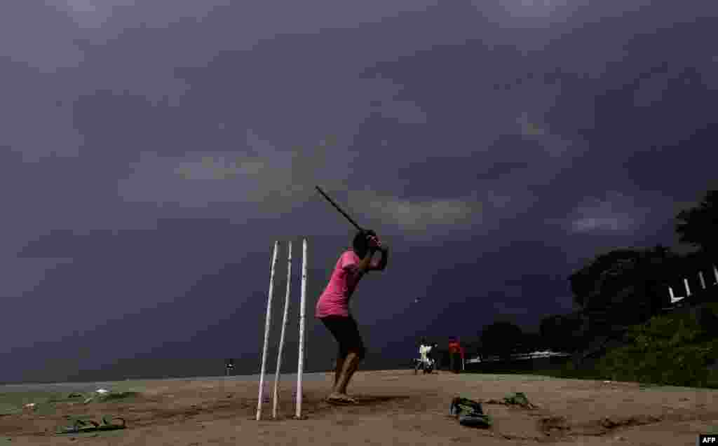 Children play cricket as rain clouds loom over the Brahmaputra River in Guwahati, capital of northeastern Assam state, India.