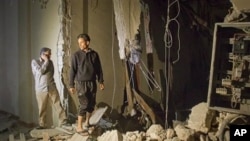 In this photo taken on a government organized tour, officials inspect damage at a building following an airstrike in Tripoli, Libya, early Saturday, April 30, 2011
