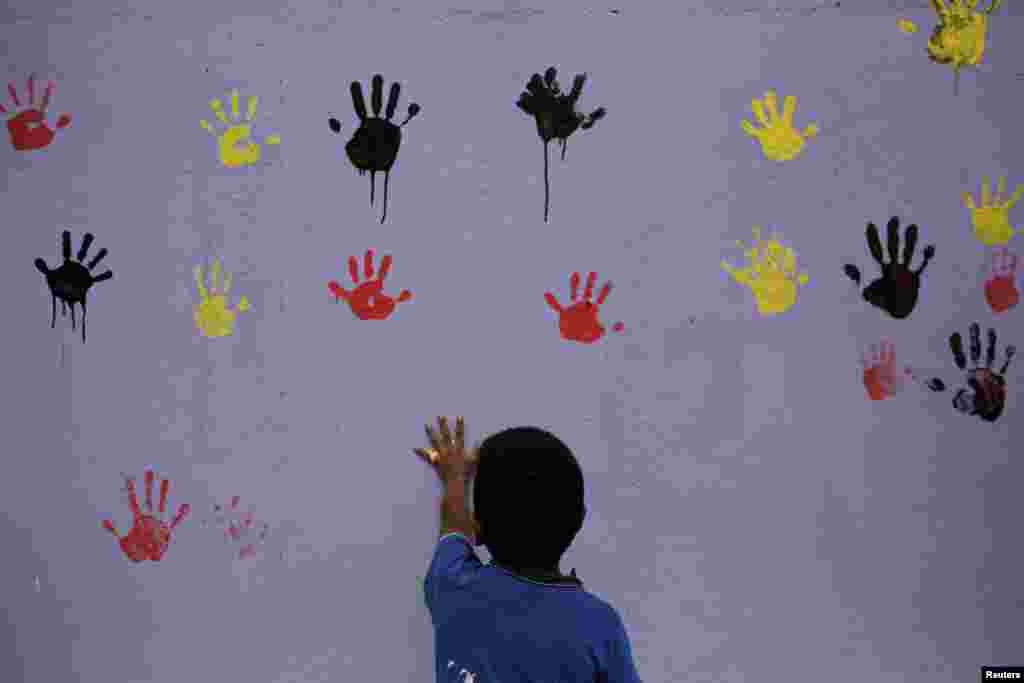 A child leaves his handprint on a freshly painted wall, which was covered with graffiti associated with the Mara Salvatrucha gang, during an operation aimed to erase gang-related graffiti at the El Bucaro settlement in Guatemala City, Guatemala.