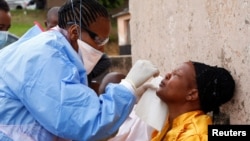 A health worker wearing a protective suit takes a swab from a resident during a door-to-door testing in an attempt to contain the coronavirus disease (COVID-19) outbreak. REUTERS/Rogan Ward