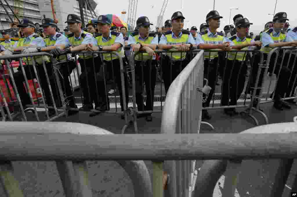 Police officers stand guard outside a flag-raising ceremony where Hong Kong's embattled leader attended a ceremony to mark China's National Day in Hong Kong, Oct. 1, 2014.