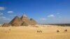 Les touristes sur des chameaux sur le site historique de la Pyramides de Gizeh à Gizeh, près du Caire, en Egypte, le jeudi 9 Avril 2015.