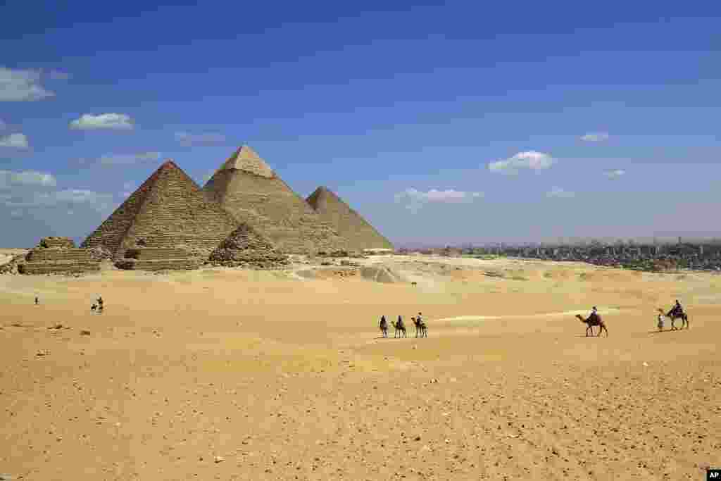 Tourists ride camels at the site of the Giza Pyramids in Giza, near Cairo, Egypt.