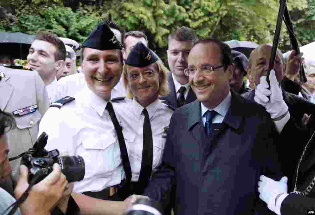French President Francois Hollande (R) poses for pictures with French army female officers during a reception, on July 13, 2012 at the Hotel de Brienne Defence Ministry in Paris, in honor of the French troops who will parade the following day on the Champ