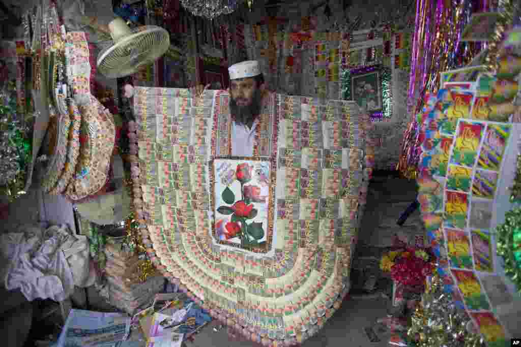 Pakistani shopkeeper Talib Hussain displays a giant sized money garland to customers in Bannu, June 18, 2014. These traditional garlands are made of local currency notes and are gifted to grooms by their friends and relatives in marriages. The garlands usually worth between rupees 5,000-10,000 (US$60-100).