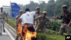 Indian policemen try to extinguish fire on Sherab Tsedor, a Tibetan resident of New Delhi, outside the Chinese Embassy, New Delhi, November 4, 2011.