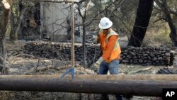 FILE - In this Oct. 18, 2017 file photo, a Pacific Gas & Electric worker replaces power poles destroyed by wildfires in Glen Ellen, Calif. California fire officials say sagging PG&E power lines that made contact ignited a blaze.