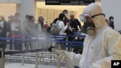 ILUSTRACIJA - Putnici na aerodromu dok osoblje vrši dezinfekciju od virusa (Foto: AP/Hassan Ammar)