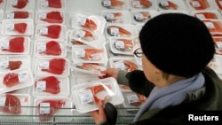 FILE - A customer is seen picking out a fish fillet at a supermarket of French grocery retailer Auchan, in Moscow, Jan. 15, 2015.