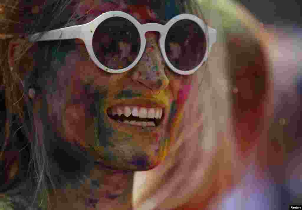 A woman with colored powder smeared on her face smiles as she celebrates Holi, the Festival of Colors, in Kathmandu, Nepal.