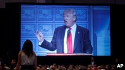 A demonstrator stands on a chair and yells as Republican presidential candidate Donald Trump delivers an economic policy speech to the Detroit Economic Club, Monday, Aug. 8, 2016.