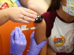 FILE - Parker McKenzie, 10, right, receives a Pfizer COVID-19 vaccine from a nurse practitioner during a COVID-19 vaccine clinic at Nationwide Children's Hospital in Columbus, Ohio, Nov. 3, 2021.