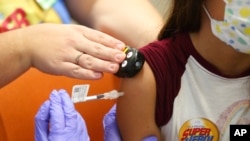 FILE - A 10-year-old girl, right, receives a Pfizer COVID-19 vaccine from a nurse during a COVID-19 vaccine clinic at Nationwide Children's Hospital in Columbus, Ohio, Nov. 3, 2021. 