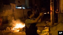 Officers of the Police Pacification Unit patrol next to a burning barricade during clashes at the Pavao Pavaozinho slum in Rio de Janeiro, Brazil, Tuesday, April 22, 2014.