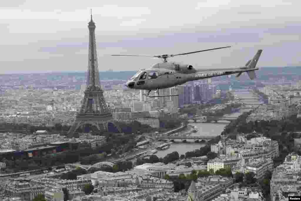 A French army helicopter flies past the Eiffel tower on its way to the Bastille Day parade in Paris, July 14, 2014.