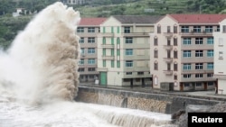 A wave, under the influence of Typhoon Chan-hom, hits the shore next to residential buildings in Wenling, Zhejiang province, China, July 10, 2015. 