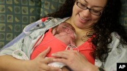 In this Tuesday, March 15, 2016 photo, mother Angelica Juarez holds Olivia Niedermeyer, one of her preemie twin daughters after Olivia and sister Evelyn underwent eye exams at Advocate Children's Hospital in Chicago.