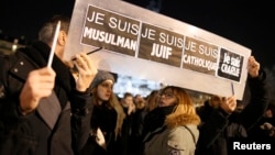 People hold a placard which reads "I am Muslim, I am Jewish, I am Catholic, I am Charlie" at a vigil, following the shooting of 12 people at the satirical newspaper Charlie Hebdo, at the Place de la Republic in Paris, Jan. 8, 2015.