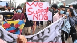 FILE - Protesters hold a banner in support of the National Unity Government as they demonstrate against the military coup, in Yangon on July 7, 2021.