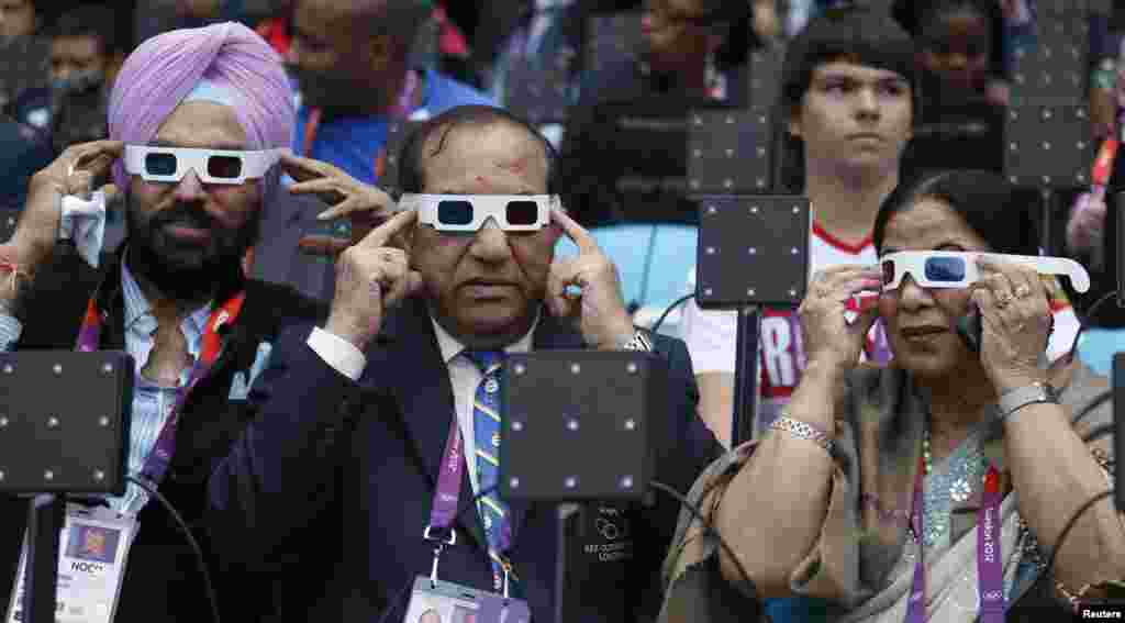 Acting Indian Olympic Association President Vijay Kumar Malhotra (C), his wife Krisha Malhotra (R) and guest Gurmit Singh (L) of India try on their glasses as they sit in the VIP box before the opening ceremony of the London 2012 Olympic Games