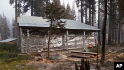 FILE - In this Sept. 2, 2021 file photo cabin partially covered in fire-resistant material stands next to properties destroyed in the Caldor Fire in Twin Bridges, Calif. Aluminum wraps designed to protect homes from flames are getting attention as wildfir