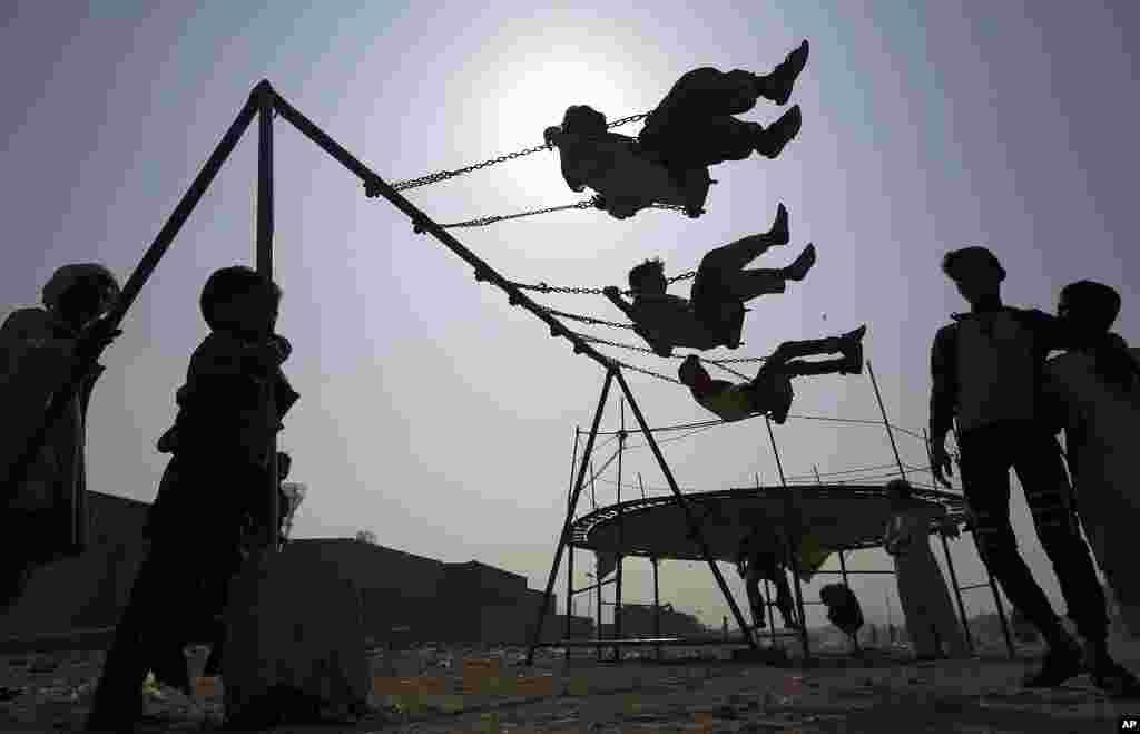Children ride swings in a playground in Karachi, Pakistan.