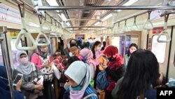 Para penumpang perempuan mengenakan masker di gerbong kereta commuter, di Jakarta, di tengah wabah COVID-19, 7 April 2020. (Foto: AFP)