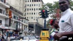 FILE - People walk past the only traffic light in Monrovia, capital of Liberia, Sept. 7, 2001.