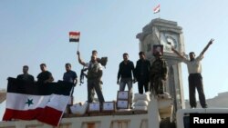 Fighters and civilians loyal to the Assad government hold up the Syrian flag after capturing the strategic town of Qusair, June 5, 2013. 