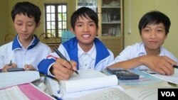 Three school children use books borrowed from a library established by philanthropist Nguyen Quang Thach