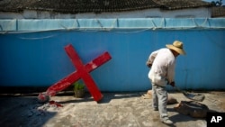 FILE - A church member shovels cement mix preparing to re-mount a cross on a Protestant church, which had been forcibly pulled down by Chinese government workers, in Taitou Village, eastern China, July 29, 2015.