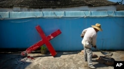 FILE - A church member shovels cement mix preparing to re-mount a cross on a Protestant church, which had been forcibly pulled down by Chinese government workers in Taitou Village, eastern China, July 29, 2015.