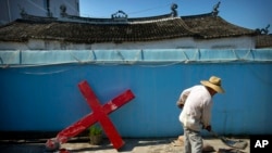 Một giáo dân đang dùng xi măng để dựng lại cây thánh giá bị nhân viên chính phủ Trung Quốc cưỡng ép tháo xuống tại nhà thờ Protestant ở làng Taitou, phía đông Trung Quốc, ngày 29/7/2015.