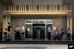 FILE - Police officers guard at the main entrance door to a building where Zion church is located after the church was shut down by authorities in Beijing, Sept. 11, 2018.