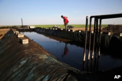 FILE - A former farmer at a primitive refinery makes crude oil into diesel and other products in Rmeilan, Hassakeh province, Syria, April 6, 2018.