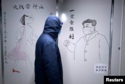 一名男子走过武汉疫情期间的一幅宣传习近平的画像。