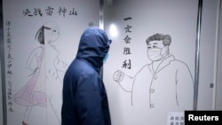 湖北省武汉市雷神山医院一名工作人员走过中国国家主席习近平戴着口罩的素描海报。该医院于2020年初武汉爆发Covid-19新冠疫情后火速建成。