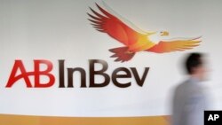 FILE - A man walks past the AB InBev logo in Leuven, Belgium.