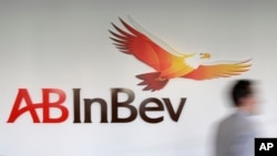FILE - A man walks past the AB InBev logo in Leuven, Belgium.