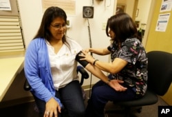 In this photo taken April 11, 2013, Liz DeRouen, 49, left, gets her blood pressure checked by medical assistant Jacklyn Stra at the Sonoma County Indian Health Project in Santa Rosa, Calif.