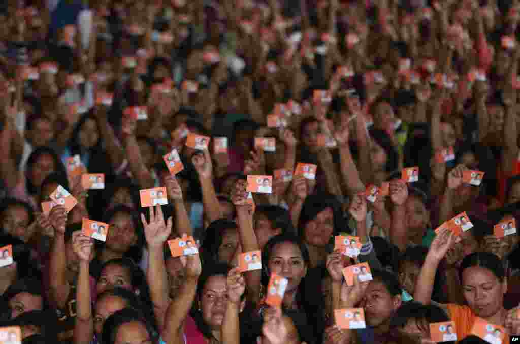 Filipino residents raise cards with a photo of former President and now Manila Mayor Joseph Estrada, as they wait during a Christmas gift-giving by the local government in the slum district of Tondo in Manila, Philippines.