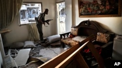 FILE - A U.S.-backed Syrian Democratic Forces fighter looks through a window as he takes his position inside a destroyed apartment on the front line, in Raqqa, northeast Syria, July 27, 2017.