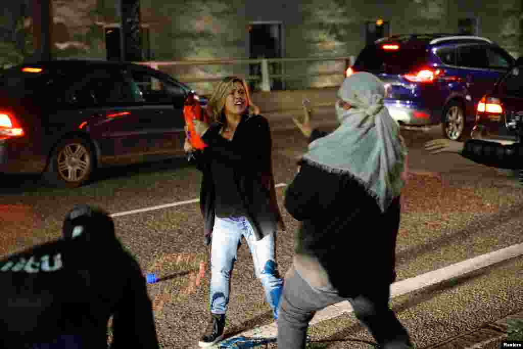 A motorist who was caught in the middle of a riot threatens a demonstrator with detergent during a protest against the election of Republican Donald Trump as president of the United States in Portland, Oregon, Nov. 10, 2016.