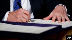 FILE - President Donald Trump signs the "Department of Veterans Affairs Accountability and Whistleblower Protection Act of 2017" in the East Room of the White House, June 23, 2017, in Washington. 