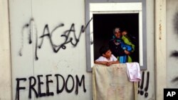 A woman holds a baby inside a shelter at the Greek northern point of Idomeni, Greece, May 3, 2016.