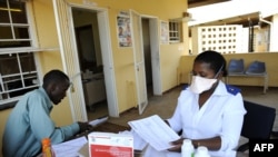 FILE - A patient waits for his pills as he meets with a nurse at Nhlangano health center in Swaziland, Oct. 28, 2009. 